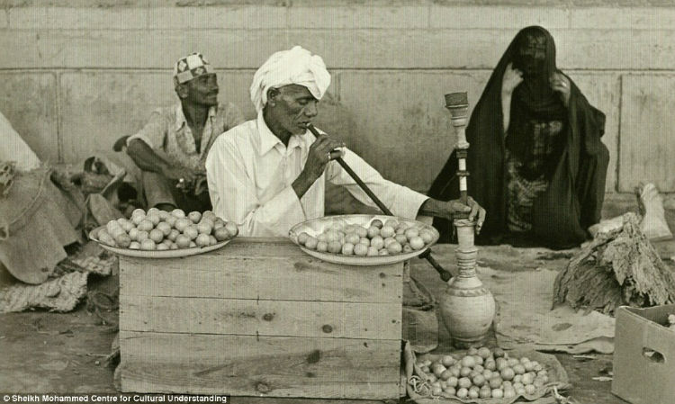 A man smelling lemons and herbs, while smoking a shisha