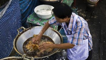 Picture Thai cook fries chicken burning-hot oil with his completely bare hands.